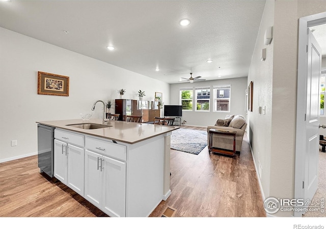551 Vicot Way Unit D, Fort Collins, CO 80524 - kitchen with stainless steel dishwasher, light wood finished floors, white cabinetry, ceiling fan, and a kitchen island with sink