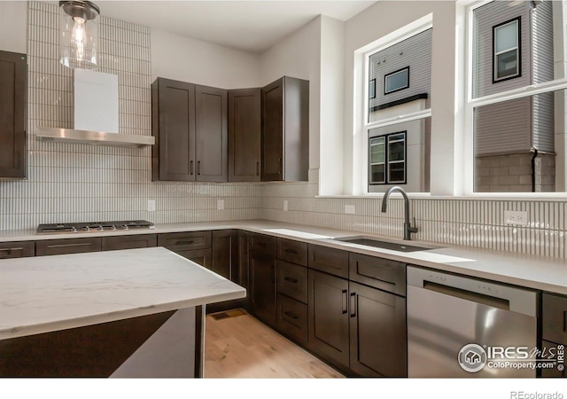 362 Promenade Dr, Superior, CO 80027 - kitchen featuring appliances with stainless steel finishes, dark brown cabinetry, decorative backsplash, light wood-type flooring, and decorative light fixtures