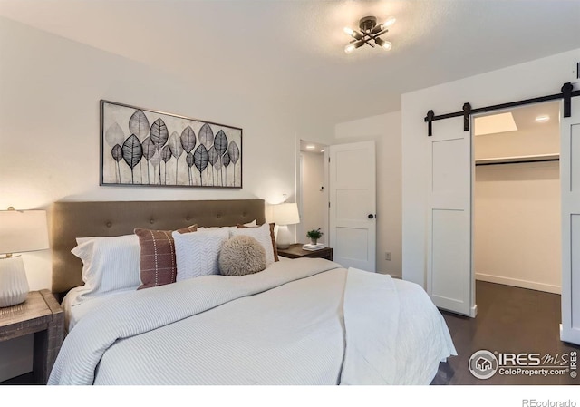 3250 Oneal Cir Unit 10, Boulder, CO 80301 - bedroom featuring a barn door, a spacious closet, dark wood-style floors, and a closet
