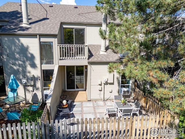 4863 W Moorhead Cir, Boulder, CO 80305 - rear view of house featuring roof with shingles, a balcony, a fenced front yard, and a patio area