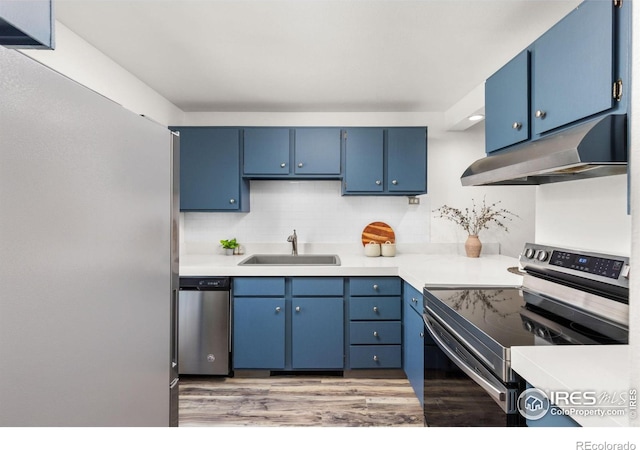 4863 W Moorhead Cir, Boulder, CO 80305 - kitchen with appliances with stainless steel finishes, under cabinet range hood, blue cabinets, light wood finished floors, and light countertops