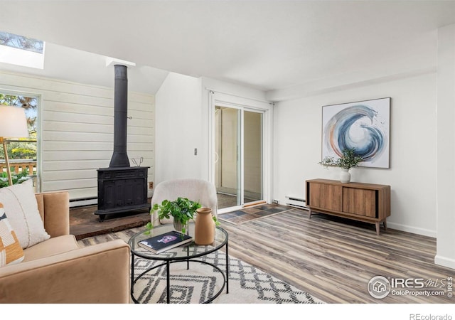 4863 W Moorhead Cir, Boulder, CO 80305 - living room featuring a wood stove, wood finished floors, a skylight, and a baseboard radiator