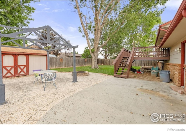 3207 Valmont St, Evans, CO 80620 - fenced backyard featuring a fire pit, stairs, a wooden deck, a patio area, and an outdoor structure
