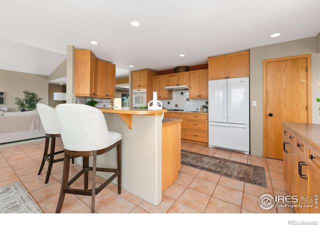 102 Bear Hollow Rd, Laporte, CO 80535 - kitchen with white appliances, a kitchen breakfast bar, light tile patterned flooring, a peninsula, and under cabinet range hood