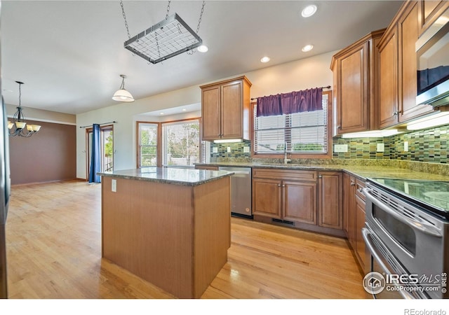 137 Reid Rd, Fort Morgan, CO 80701 - kitchen featuring appliances with stainless steel finishes, a center island, tasteful backsplash, brown cabinetry, and plenty of natural light