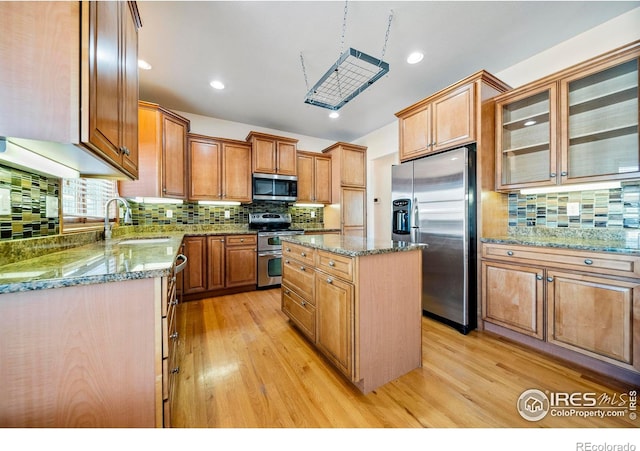 137 Reid Rd, Fort Morgan, CO 80701 - kitchen with appliances with stainless steel finishes, backsplash, light wood finished floors, a center island, and recessed lighting