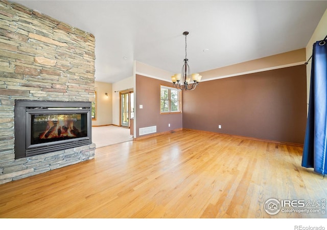 137 Reid Rd, Fort Morgan, CO 80701 - unfurnished living room with a chandelier, wood finished floors, and a stone fireplace