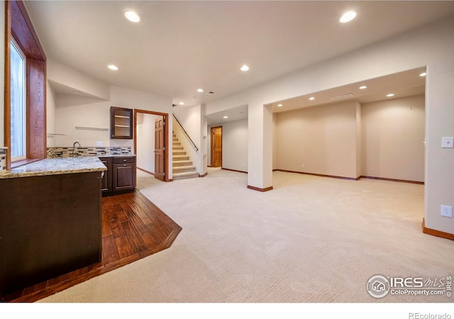 137 Reid Rd, Fort Morgan, CO 80701 - kitchen with carpet, recessed lighting, dark brown cabinets, light stone countertops, and glass insert cabinets