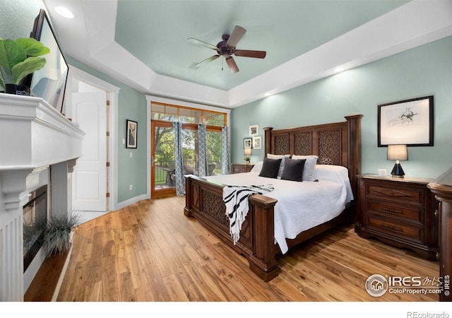 5424 Taylor Ln, Fort Collins, CO 80528 - bedroom featuring access to outside, a tray ceiling, light wood-type flooring, a fireplace, and ceiling fan