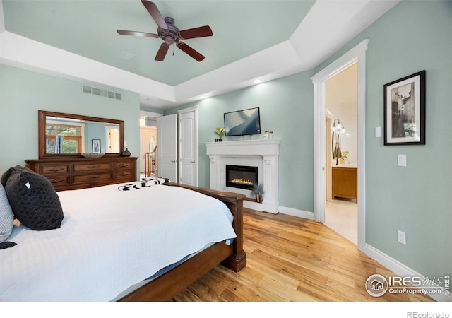 5424 Taylor Ln, Fort Collins, CO 80528 - bedroom with light wood-style flooring, a glass covered fireplace, connected bathroom, a ceiling fan, and a closet