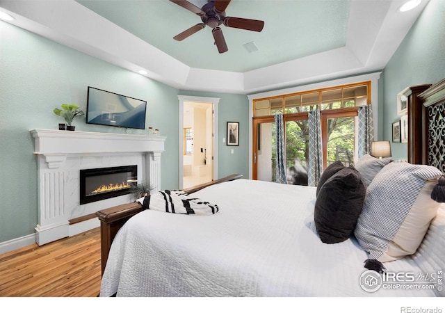 5424 Taylor Ln, Fort Collins, CO 80528 - bedroom featuring wood finished floors, a raised ceiling, a high end fireplace, recessed lighting, and access to outside