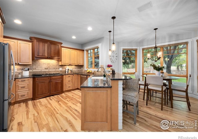 5424 Taylor Ln, Fort Collins, CO 80528 - kitchen featuring stainless steel appliances, a peninsula, light wood-style floors, a kitchen bar, and backsplash