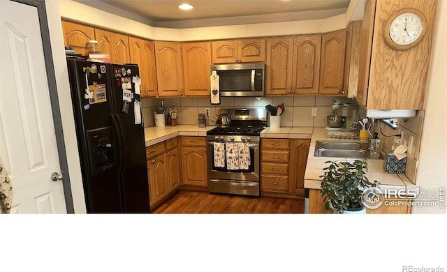 205 Timber Ridge Ct, Severance, CO 80550 - kitchen with stainless steel appliances, brown cabinets, decorative backsplash, tile countertops, and dark wood-style flooring