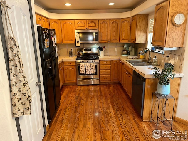 205 Timber Ridge Ct, Severance, CO 80550 - kitchen with black appliances, dark wood finished floors, brown cabinetry, tasteful backsplash, and recessed lighting