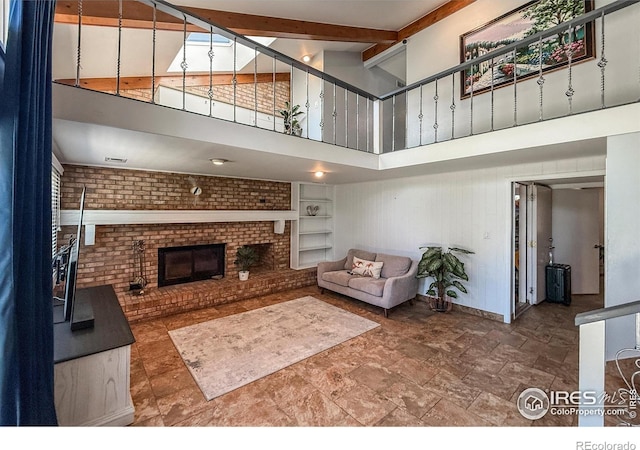 5004 Fox Hill Dr, Longmont, CO 80504 - living room featuring a high ceiling, a brick fireplace, built in shelves, beam ceiling, and stone finish flooring