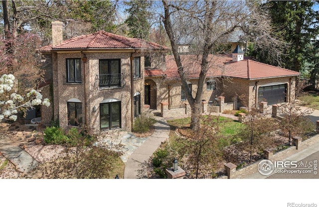 2111 E Alameda Ave, Denver, CO 80209 - mediterranean / spanish home with a tiled roof, a balcony, an attached garage, a chimney, and stucco siding
