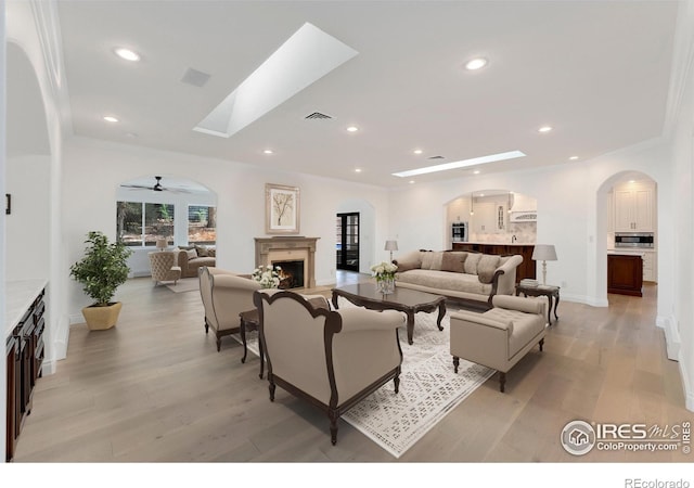 2111 E Alameda Ave, Denver, CO 80209 - living area with a lit fireplace, light wood finished floors, arched walkways, recessed lighting, and crown molding