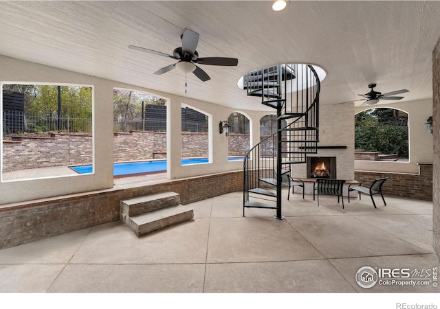 2111 E Alameda Ave, Denver, CO 80209 - view of patio with a ceiling fan, a lit fireplace, and stairs