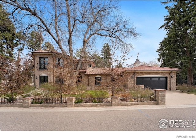 2111 E Alameda Ave, Denver, CO 80209 - view of front facade with a garage, a fenced front yard, concrete driveway, a tiled roof, and brick siding