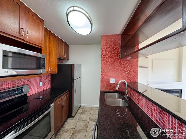 3025 Broadway St Unit 17, Boulder, CO 80304 - kitchen with stainless steel appliances, decorative backsplash, dark stone counters, light tile patterned floors, and brown cabinets