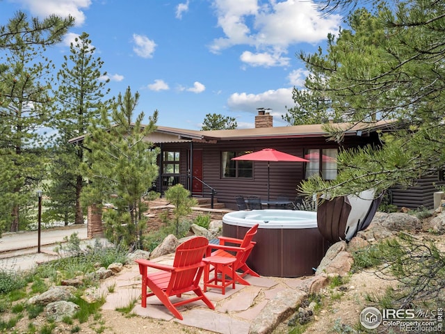 1650 Powelly Ln, Estes Park, CO 80517 - back of house with a hot tub, a chimney, and a patio area
