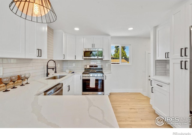 7826 Joan Dr, Denver, CO 80221 - kitchen featuring appliances with stainless steel finishes, light wood-style floors, backsplash, white cabinets, and light stone countertops