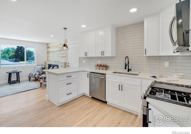 7826 Joan Dr, Denver, CO 80221 - kitchen featuring stainless steel appliances, light wood-type flooring, backsplash, white cabinets, and a peninsula
