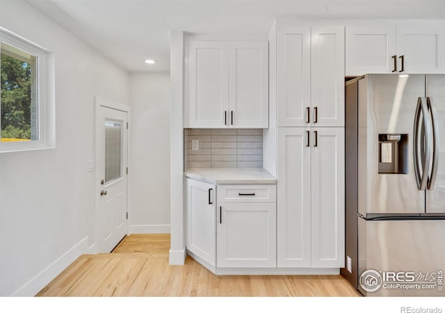 7826 Joan Dr, Denver, CO 80221 - kitchen with stainless steel refrigerator with ice dispenser, light wood-style flooring, white cabinets, recessed lighting, and decorative backsplash