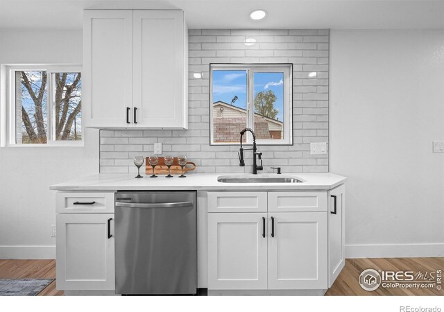 9230 Aspen Dr, Thornton, CO 80229 - kitchen featuring dishwasher, white cabinets, light countertops, tasteful backsplash, and light wood-style floors