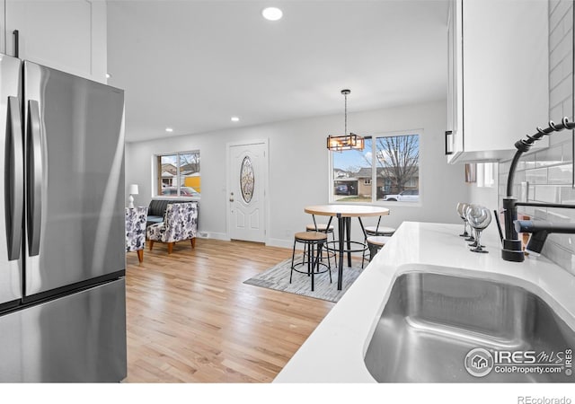 9230 Aspen Dr, Thornton, CO 80229 - kitchen with freestanding refrigerator, recessed lighting, light wood finished floors, white cabinetry, and light countertops
