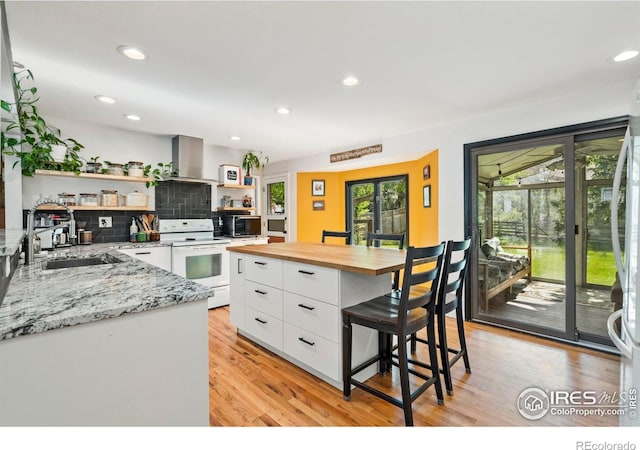 7423 Saulsbury St, Arvada, CO 80003 - kitchen with white electric range oven, open shelves, butcher block countertops, white cabinetry, and a kitchen bar