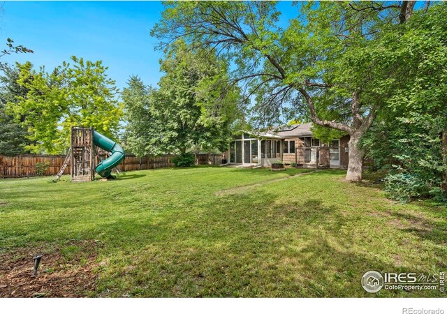 7423 Saulsbury St, Arvada, CO 80003 - fenced backyard featuring a playground and a sunroom