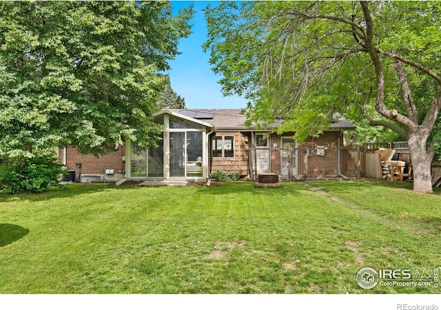 7423 Saulsbury St, Arvada, CO 80003 - back of property featuring a sunroom, solar panels, and brick siding