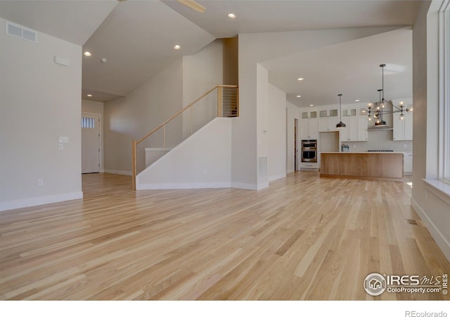 961 Eldorado Ln, Louisville, CO 80027 - unfurnished living room featuring light wood-type flooring, a chandelier, stairs, recessed lighting, and high vaulted ceiling