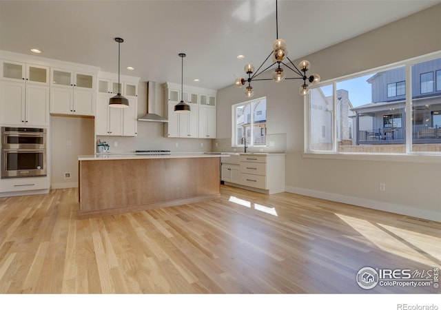 961 Eldorado Ln, Louisville, CO 80027 - kitchen with wall chimney exhaust hood, stainless steel double oven, light wood-style floors, white cabinetry, and recessed lighting