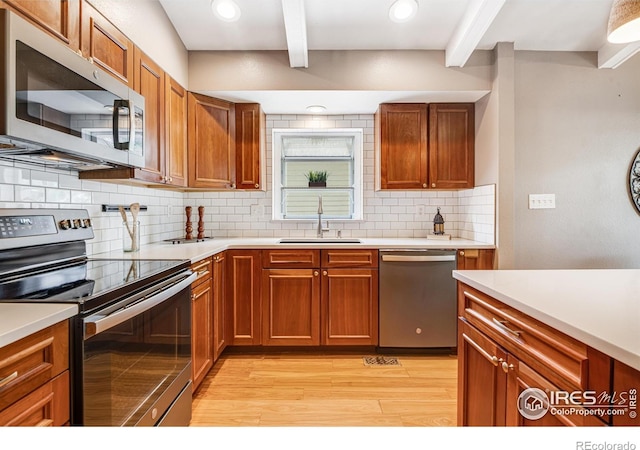 2213 Hiawatha Ct, Fort Collins, CO 80525 - kitchen featuring appliances with stainless steel finishes, beam ceiling, light wood-style flooring, light countertops, and decorative backsplash
