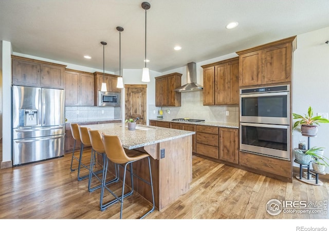 1897 Holloway Dr, Windsor, CO 80550 - kitchen with appliances with stainless steel finishes, wall chimney exhaust hood, light wood-style flooring, backsplash, and recessed lighting