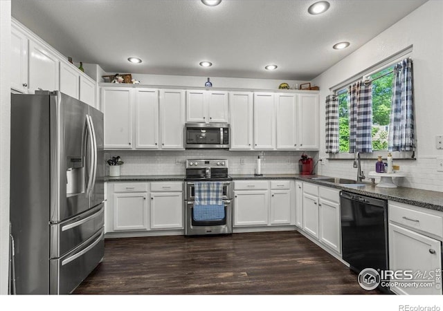 11861 Fairplay St, Commerce City, CO 80603 - kitchen featuring stainless steel appliances, dark countertops, white cabinetry, decorative backsplash, and recessed lighting