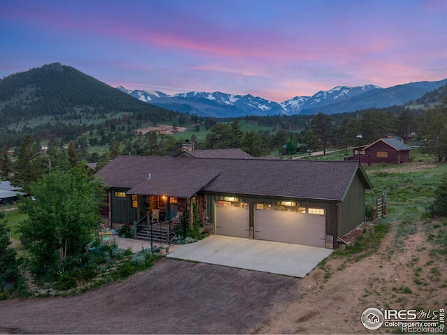 2055 Siskin Dr, Estes Park, CO 80517 - view of front of house featuring driveway, a garage, a mountain view, and a chimney