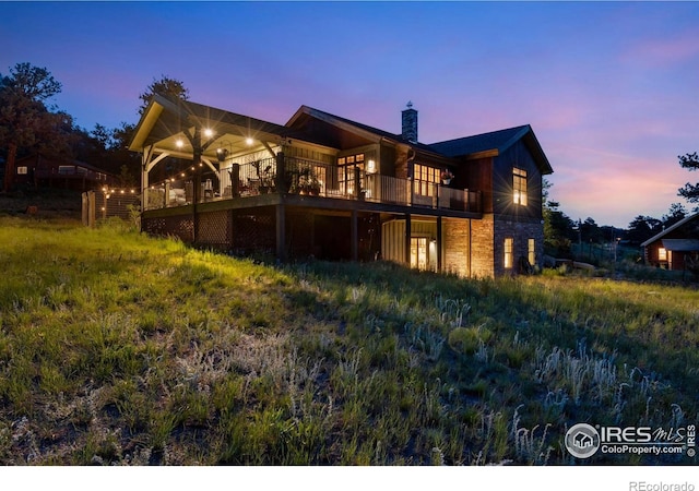 2055 Siskin Dr, Estes Park, CO 80517 - rear view of property with a chimney, stone siding, and a deck