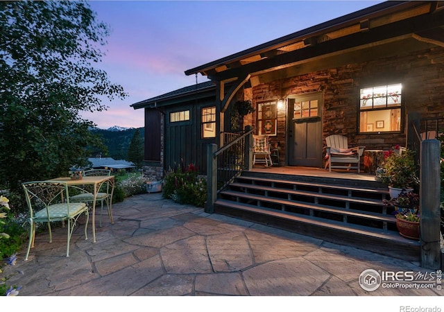 2055 Siskin Dr, Estes Park, CO 80517 - exterior entry at dusk with board and batten siding, stone siding, and covered porch