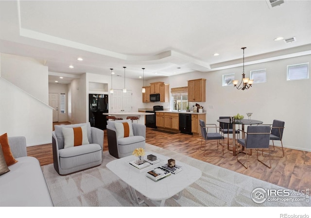 5104 Silverwood Dr, Johnstown, CO 80534 - living area with a tray ceiling, light wood finished floors, a chandelier, recessed lighting, and stairs