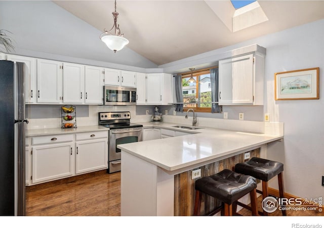 1967 Rangely Ct, Loveland, CO 80538 - kitchen with appliances with stainless steel finishes, a peninsula, a skylight, vaulted ceiling, and white cabinets