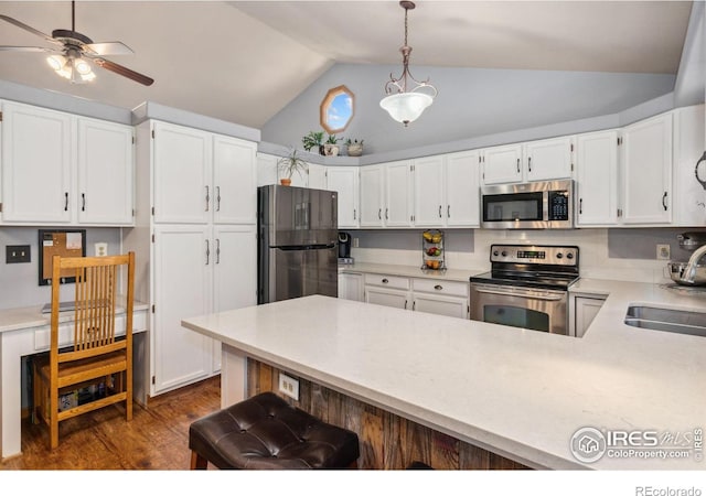 1967 Rangely Ct, Loveland, CO 80538 - kitchen with stainless steel appliances, vaulted ceiling, light countertops, a peninsula, and white cabinets