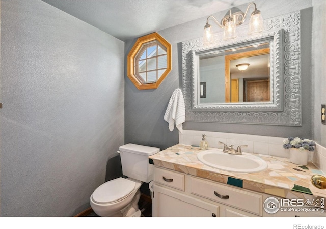 1967 Rangely Ct, Loveland, CO 80538 - half bath with vanity, a textured wall, and decorative backsplash