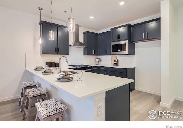 2744 Bear Springs Cir, Longmont, CO 80503 - kitchen with wall chimney exhaust hood, appliances with stainless steel finishes, light wood-type flooring, a peninsula, and recessed lighting