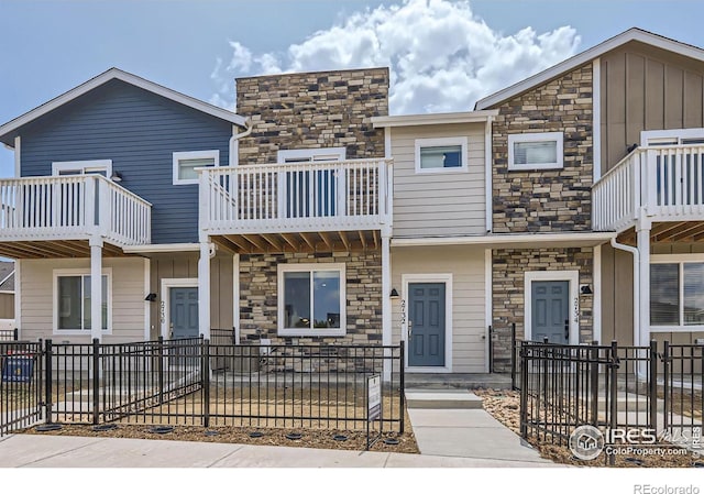 2744 Bear Springs Cir, Longmont, CO 80503 - view of property featuring stone siding, a fenced front yard, a balcony, and board and batten siding