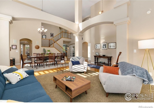 6582 Spanish Bay Dr, Windsor, CO 80550 - living room featuring arched walkways, a high ceiling, a chandelier, and decorative columns