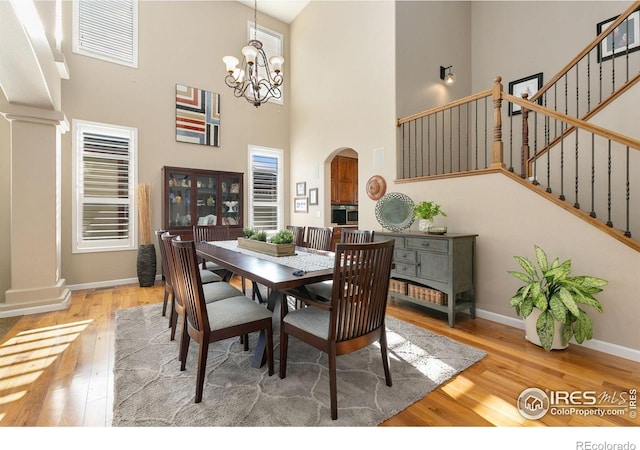 6582 Spanish Bay Dr, Windsor, CO 80550 - dining space featuring a towering ceiling, hardwood / wood-style floors, stairway, decorative columns, and arched walkways