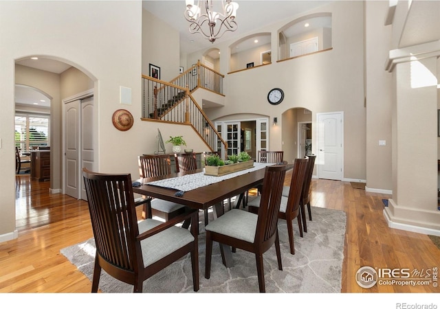 6582 Spanish Bay Dr, Windsor, CO 80550 - dining space featuring a high ceiling, arched walkways, light wood finished floors, stairs, and a chandelier